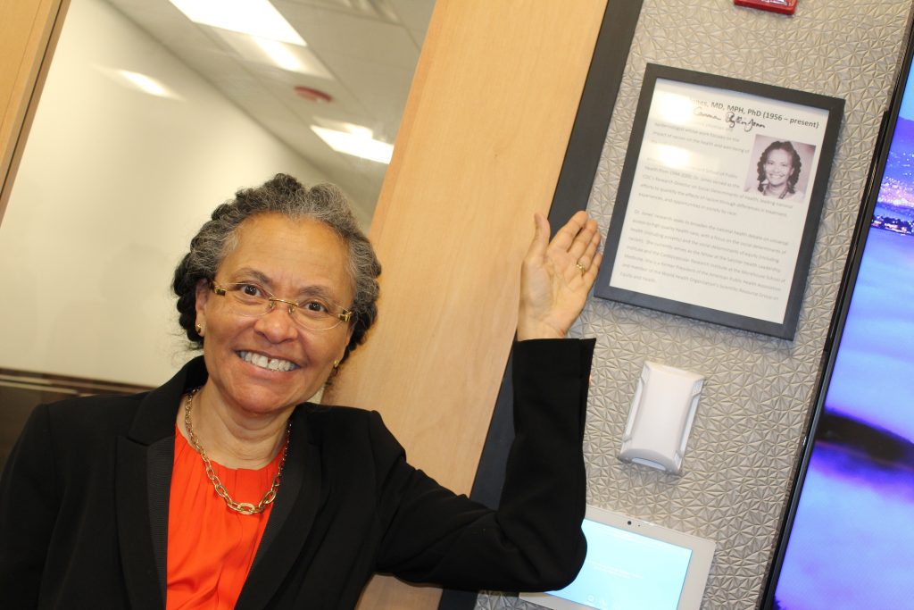 Dr. Camara Phyllis Jones posing with a framed photo of herself at ϲ headquarters