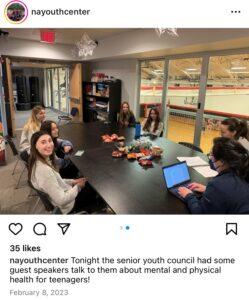 Screenshot of Instagram post by "nayouthcenter." Photo of young people gathered around a table with a window overlooking a gymnasium with caption: "tonight the senior youth council had some guest speakers talk to them about metnal and physical health for teenagers!" Dated February 8, 2023.